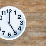 Reloj de pared sobre un fondo de madera, marcando la hora